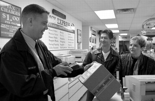 image of postal carrier scanning box while customers watch