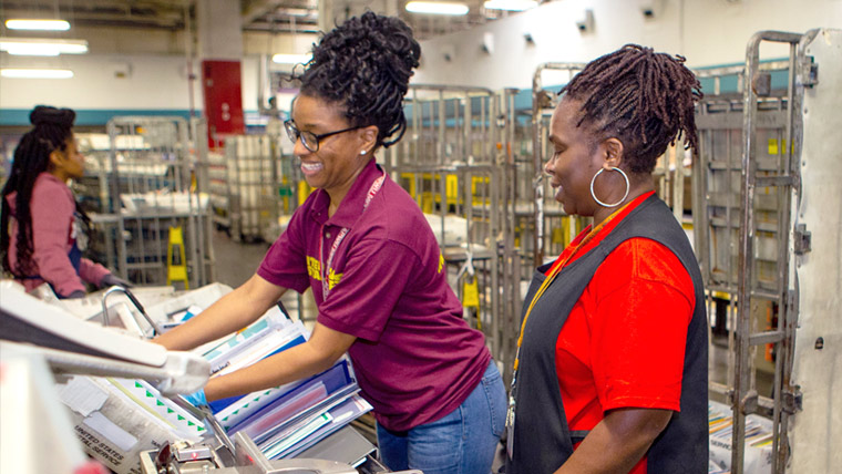 Two USPS Mail Processing Clerks inside a facility.