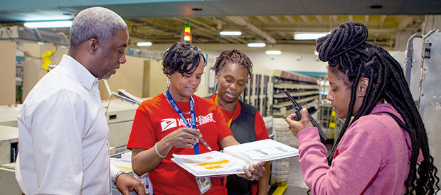 USPS employees working in a sorting facility.