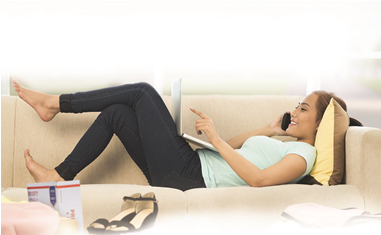 Woman on computer and cell phone relaxing on a sofa