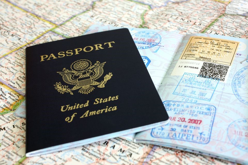Two US Passport books, one open, one closed on top of a world map