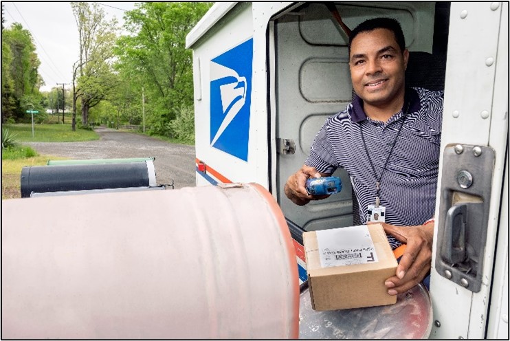 USPS Letter Carrier in truck delivering mail.