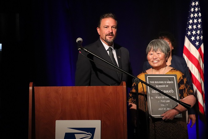 USPS Area Vice President Gregory Graves gives Leslie Sakato (George’s daughter) a replica of the plaque that will be forever in the lobby of the Stockyards Post Office.
