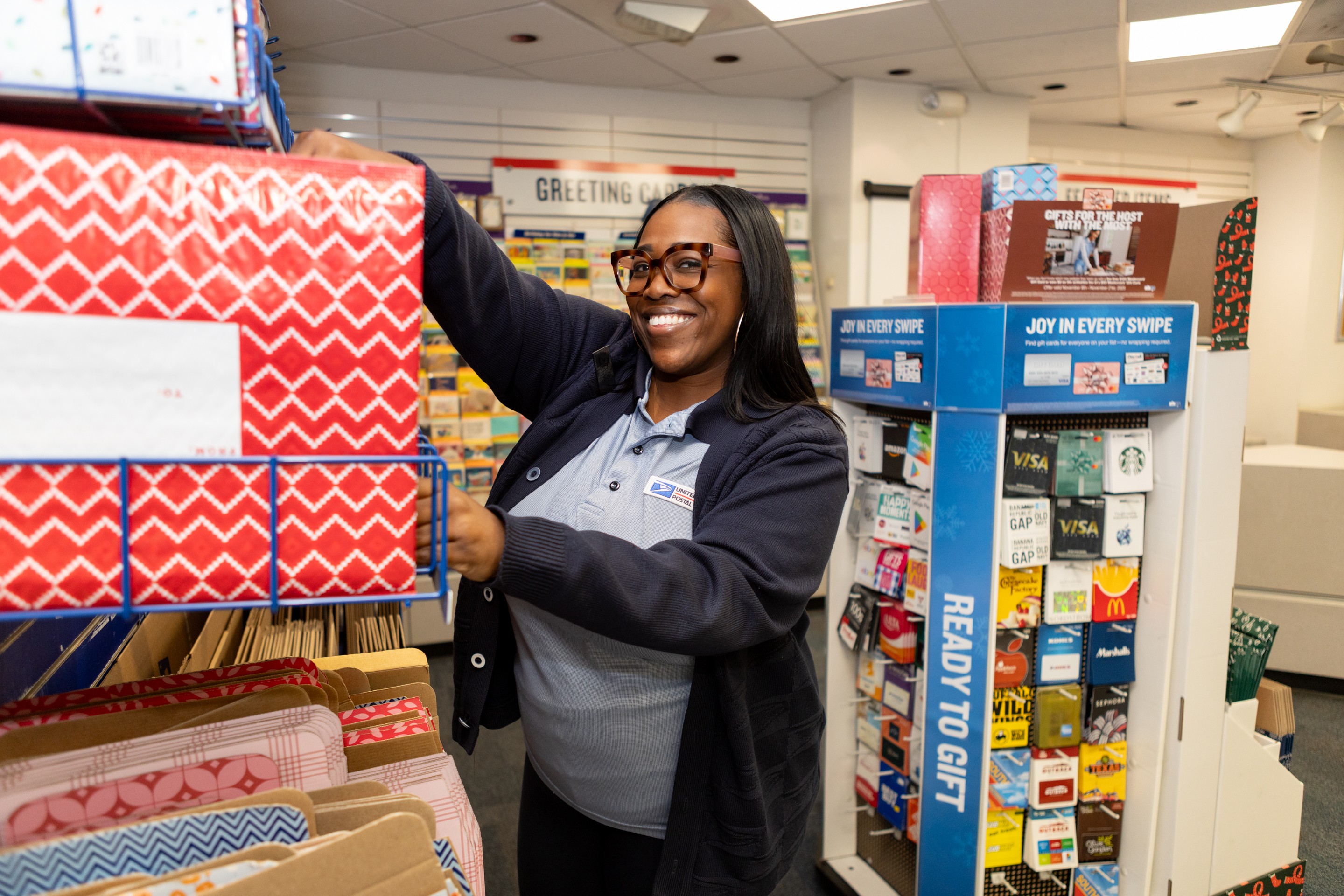 USPS retail clerk in front of display boxes