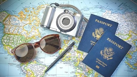 Two US Passport books on a world map with sunglasses and a camera.