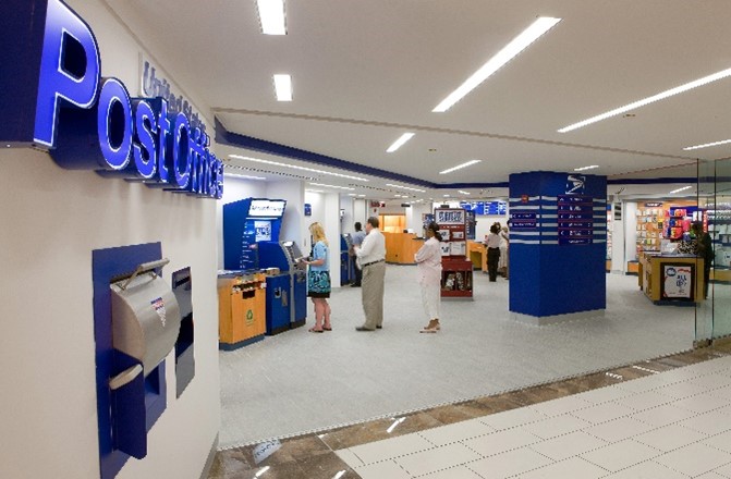 Entrance of a Post Office. Customers lined up at a kiosk.