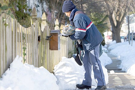 USPS Mail Carrier walking on the snow