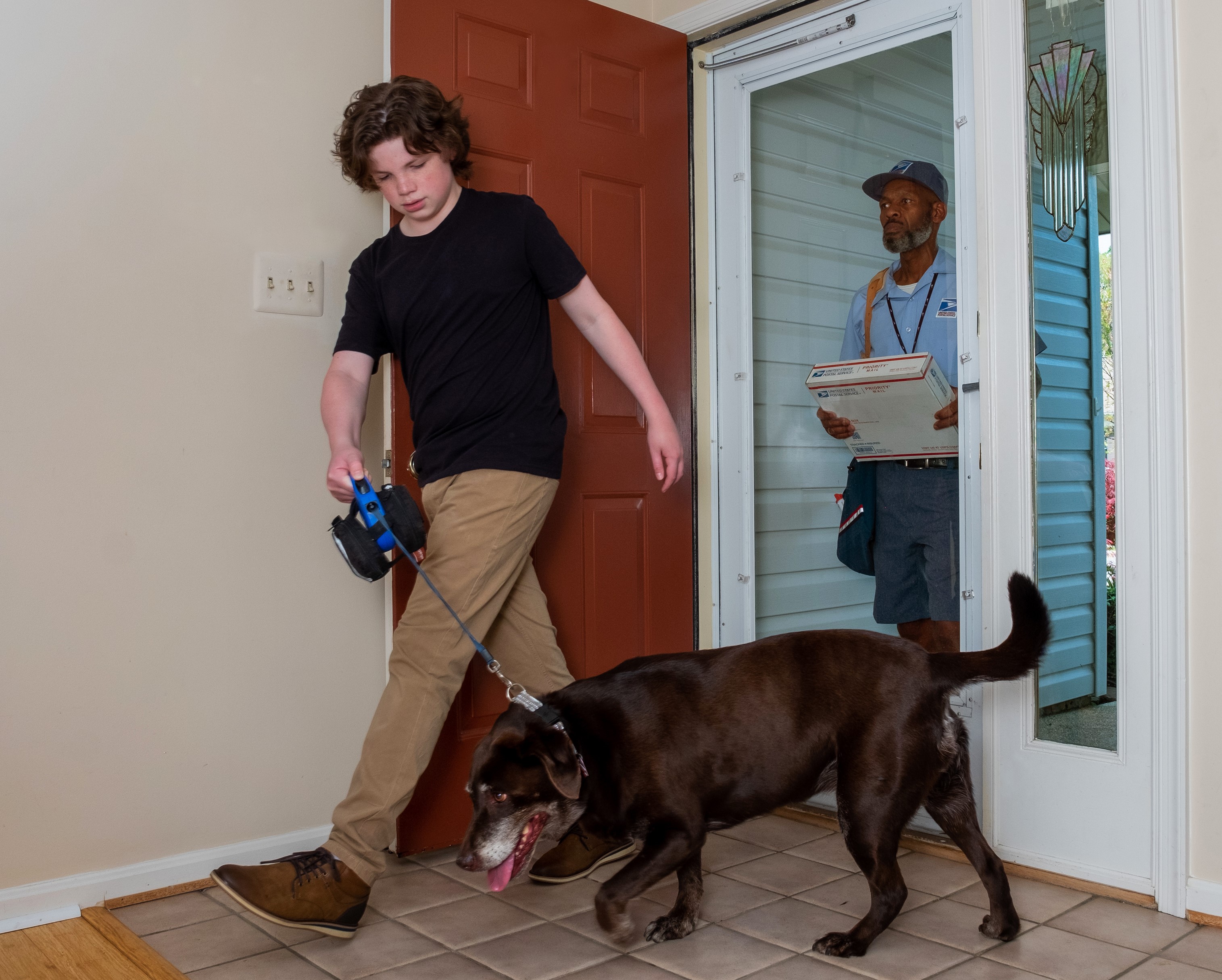 Young man leading family pet away from Letter Carrier