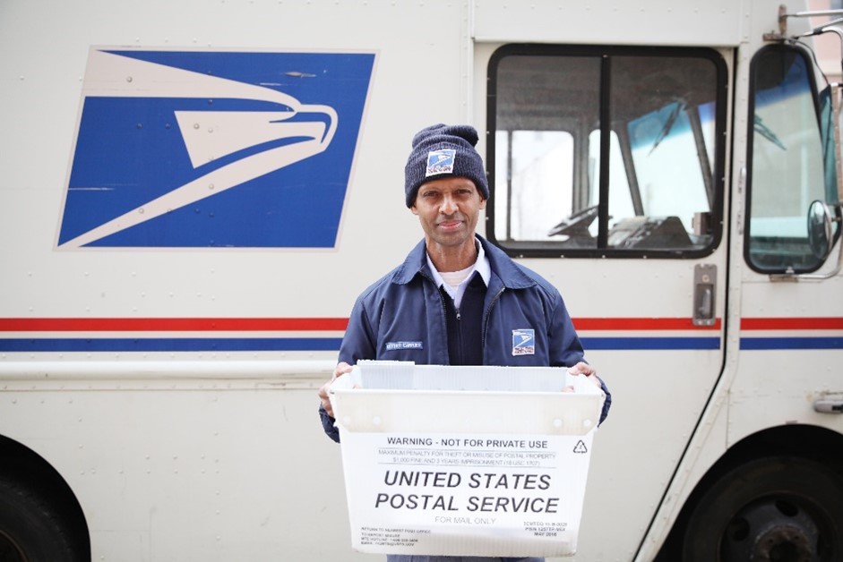 USPS Letter Carrier holding a mail bin.