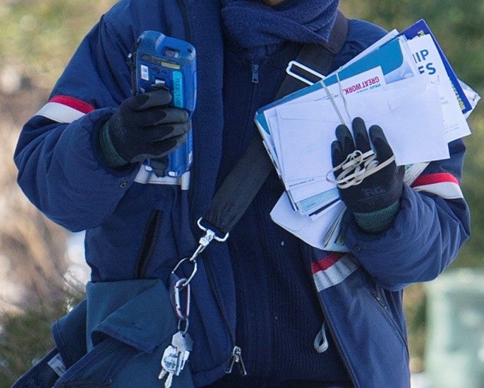 USPS carrier with scanner delivering mail