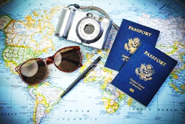 Two US Passports, a camera, sunglasses and a pen on top of a wrold map.