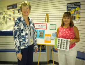 Photo below of Postmaster Anne Murray on the left presenting Patti Lord with two sheets of postage stamps bearing the image of her flamingo love mailbox.