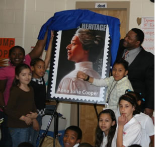 Students at Sterling Elementary School help Station Manager Britton McGill unveil the Anna Julia Cooper Stamp during a Black History event at the school last week.