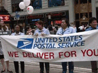 Postal Workers standing in a line holding up a 'We Deliver For You' banner