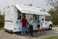 Customers in Bay St. Louis, MS, purchase stamps from the mobile Post Office