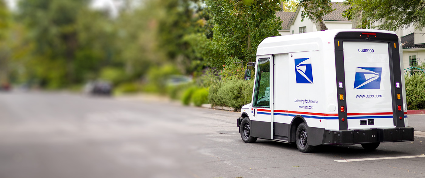 Photo of the new USPS electric delivery vehicle driving through a neighborhood.