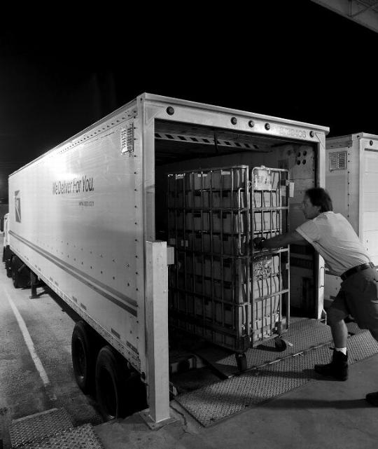 image of a postal worker loading a truck at night