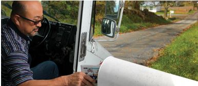 Postal carrier placing mail in mailbox.