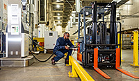 Postal employee fuelling a machine inside a large facility