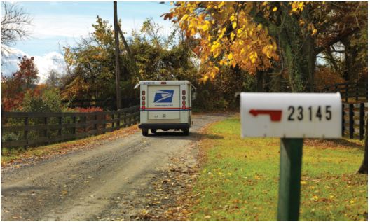 Postal vehicle driving away from a rural mailbox.