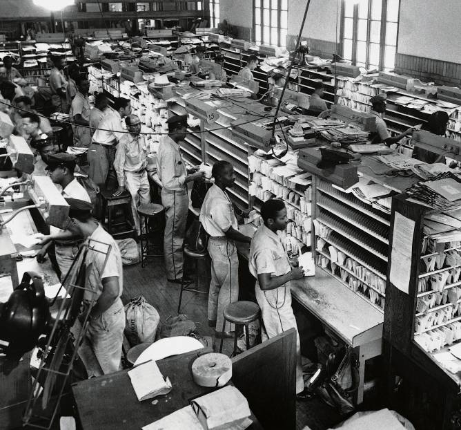 Detail of photograph of letter carriers -- both black and white -- casing mail at the Mobile, Alabama, Post Office in 1956.