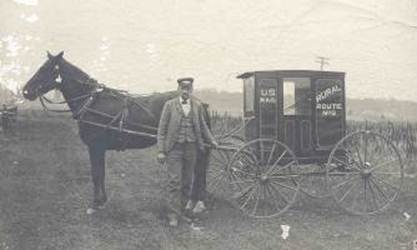 This photograph shows a letter carrier standing in front of his horse and buggy.  The words "Rural Route No. 2" and "U.S. Mail" are painted on the buggy.